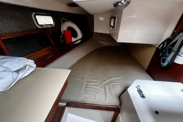 Slide: The Image of 1988 CAL Sloop interior cabin with bed, porthole, and life preserver. - 10