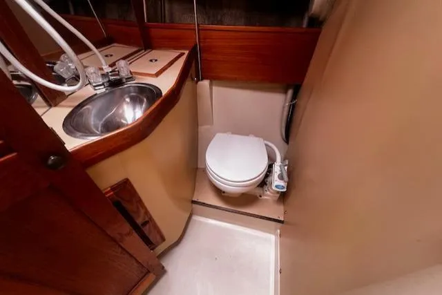 Slide: The Image of 1988 CAL Sloop bathroom with sink and toilet, featuring wood accents and compact design. - 11