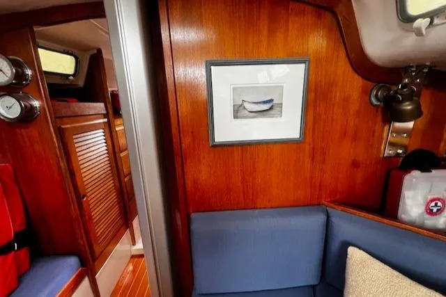 Slide: The Image of 1988 CAL Sloop interior with wood paneling, blue seating, and framed artwork. - 2