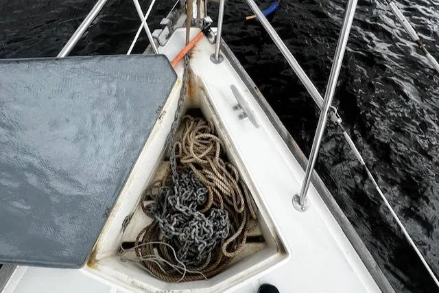 Slide: The Image of Anchor locker on 1988 CAL Sloop with ropes and chains, docked on dark water. - 20