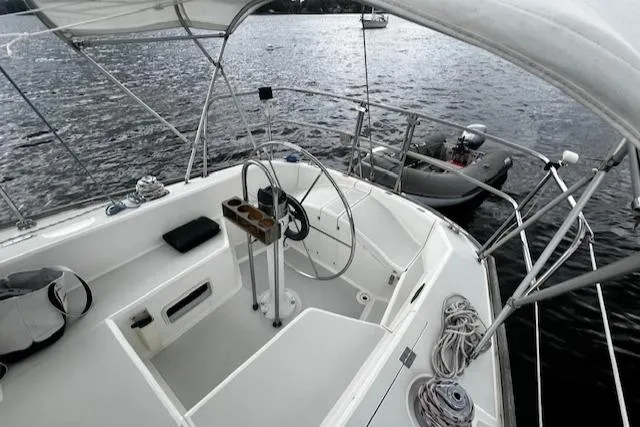 Slide: The Image of 1988 CAL Sloop sailboat cockpit with steering wheel, moored on calm water. - 22