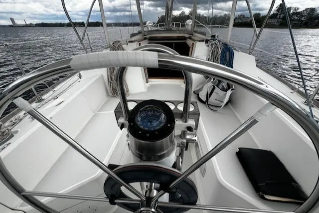 Slide: The Image of 1988 CAL Sloop sailboat cockpit with steering wheel and compass on calm water. - 26