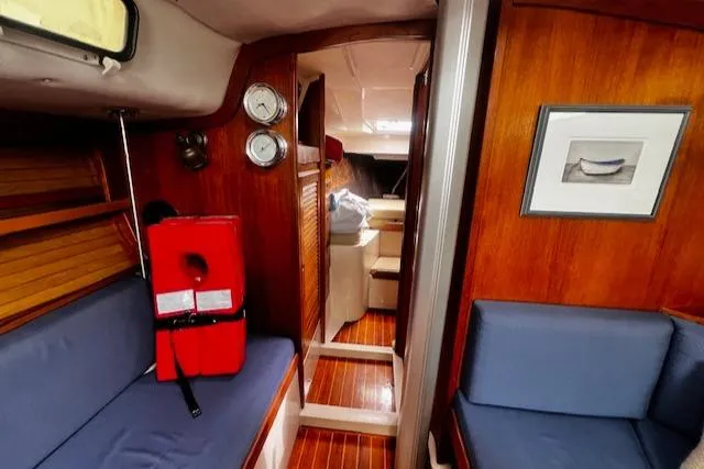 Slide: The Image of 1988 CAL Sloop interior with wooden paneling, blue seating, and nautical decor. - 3