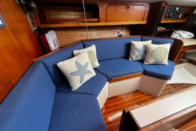 Slide: The Image of 1988 CAL Sloop interior with blue seating, nautical-themed pillows, and wooden accents. - 4