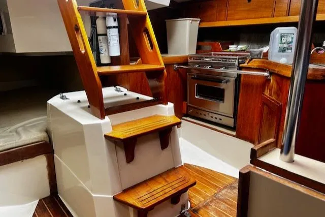 Slide: The Image of 1988 CAL Sloop interior with wooden steps, compact kitchen, and cozy cabin space. - 7