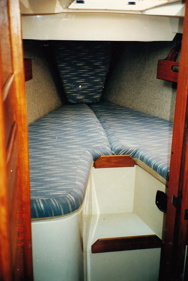 Slide: The Image of 1988 CAL Sloop interior cabin with striped cushions and wooden accents. - 9
