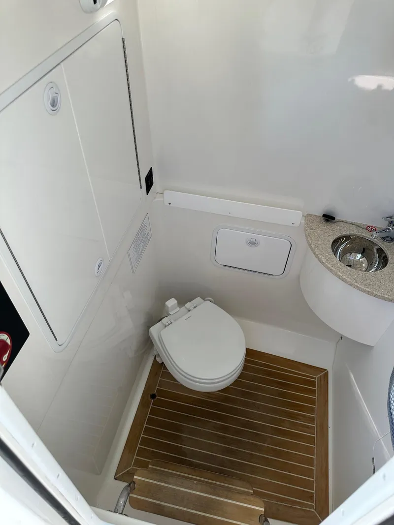 Slide: The Image of 2019 Regulator 28 boat bathroom with toilet, sink, and wooden floor. - 11