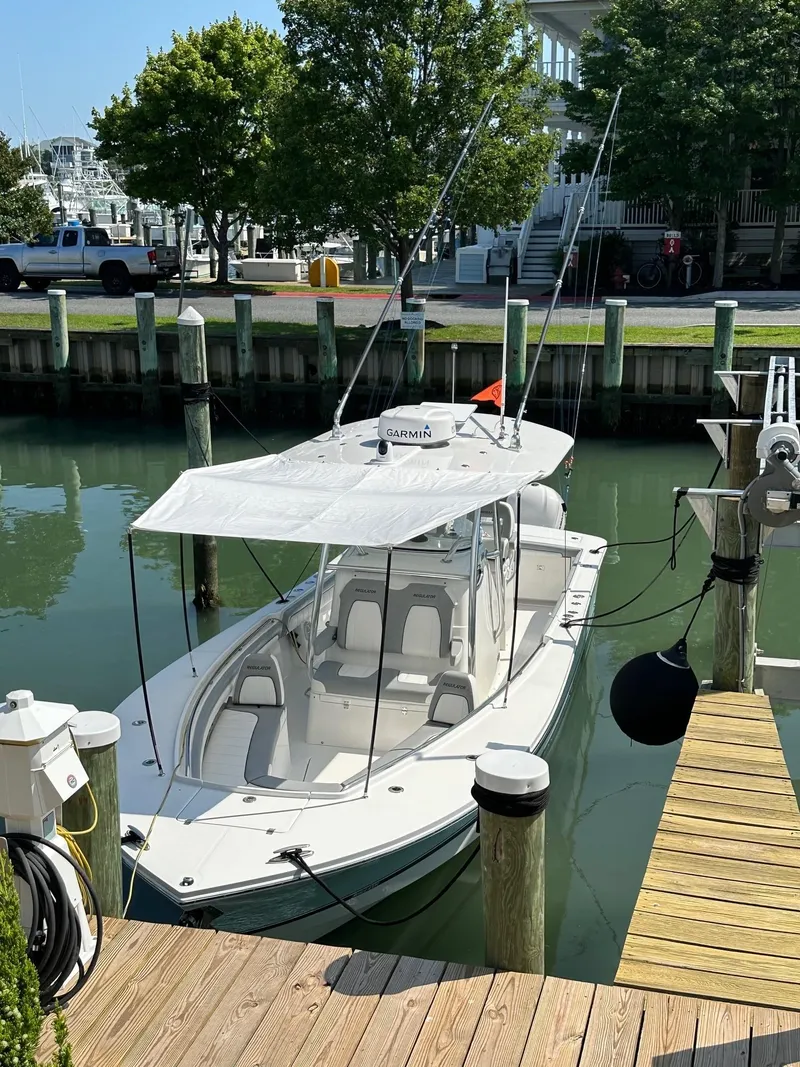 Slide: The Image of 2019 Regulator 28 boat docked in a marina with canopy and fishing rods. - 14