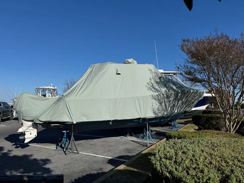 Slide: The Image of 2019 Regulator 28 boat covered and stored on stands in a parking area. - 20