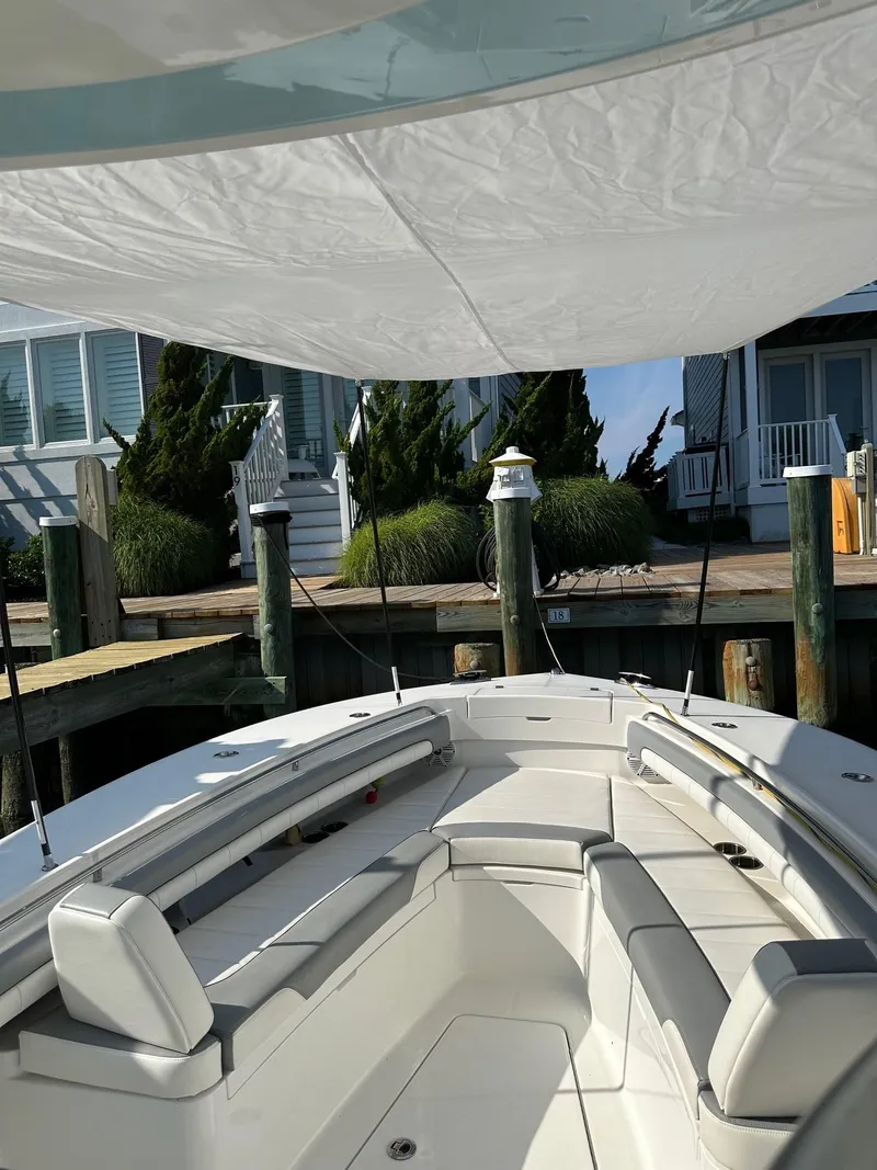 Slide: The Image of 2019 Regulator 28 boat docked, featuring spacious seating and a canopy. - 3