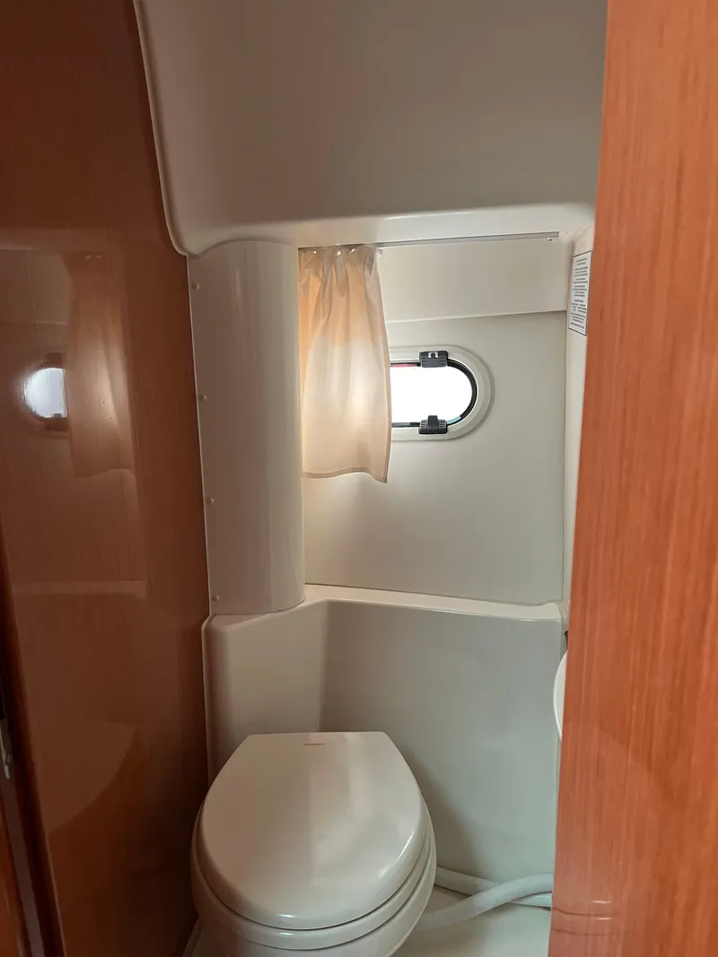 Slide: The Image of 2008 Jeanneau Prestige 34 Hardtop yacht bathroom with porthole and toilet. - 16