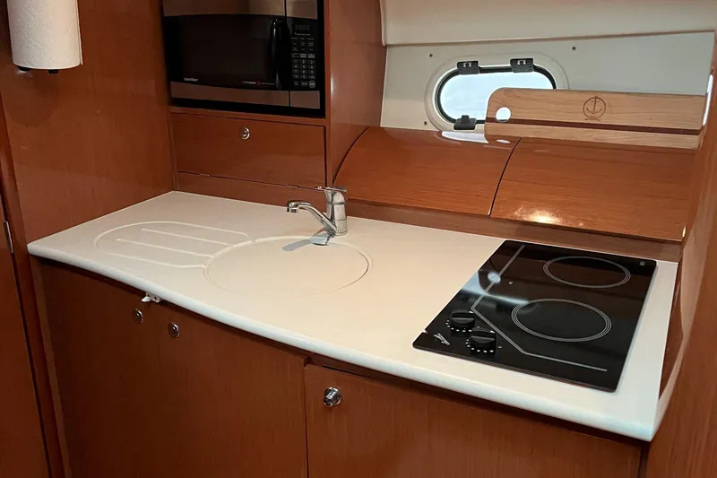 Slide: The Image of 2008 Jeanneau Prestige 34 Hardtop yacht kitchen with stove, sink, and microwave. - 22