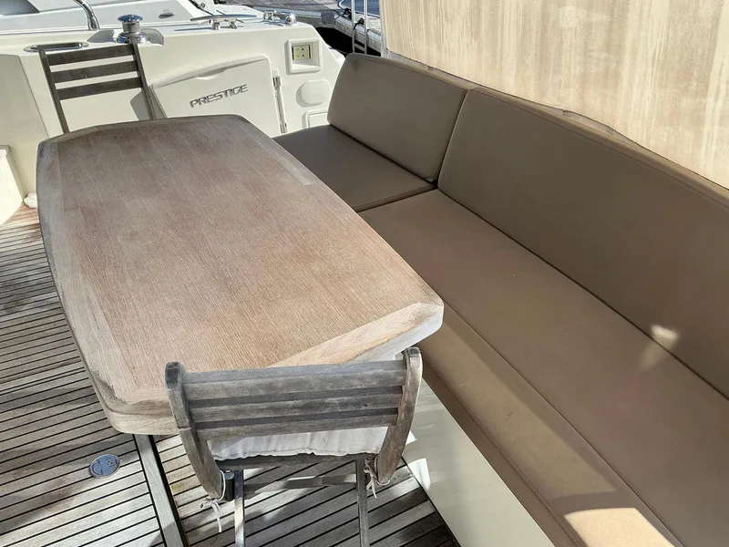 Slide: The Image of Outdoor seating area on a 2015 Prestige 500 yacht with wooden table and cushioned bench. - 16