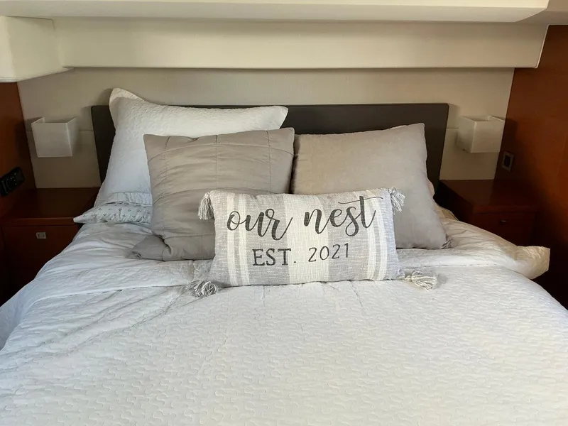 Slide: The Image of Cozy bed with decorative pillows, "Our Nest Est. 2021," in a 2015 Prestige 500 yacht. - 28