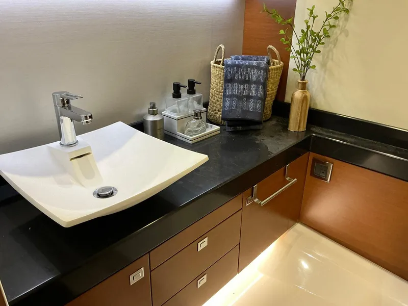 Slide: The Image of Modern bathroom sink with black countertop, wooden cabinets, and decorative plants on a Prestige 500 yacht. - 32