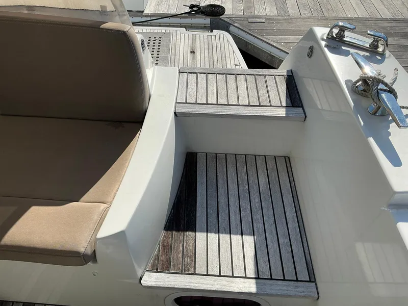 Slide: The Image of 2015 Prestige 500 yacht deck with wooden steps and beige seating. - 49