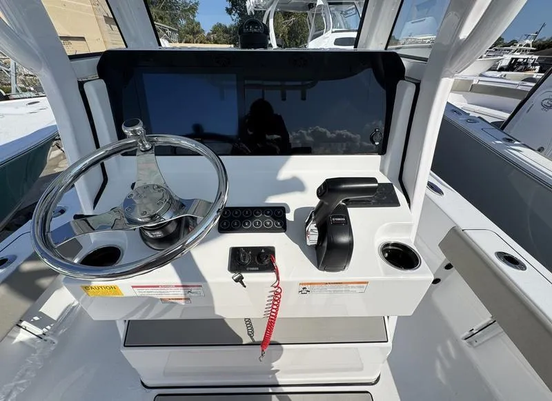 Slide: The Image of Control console of a 2025 Sportsman Masters 227 boat, featuring steering wheel and throttle. - 17