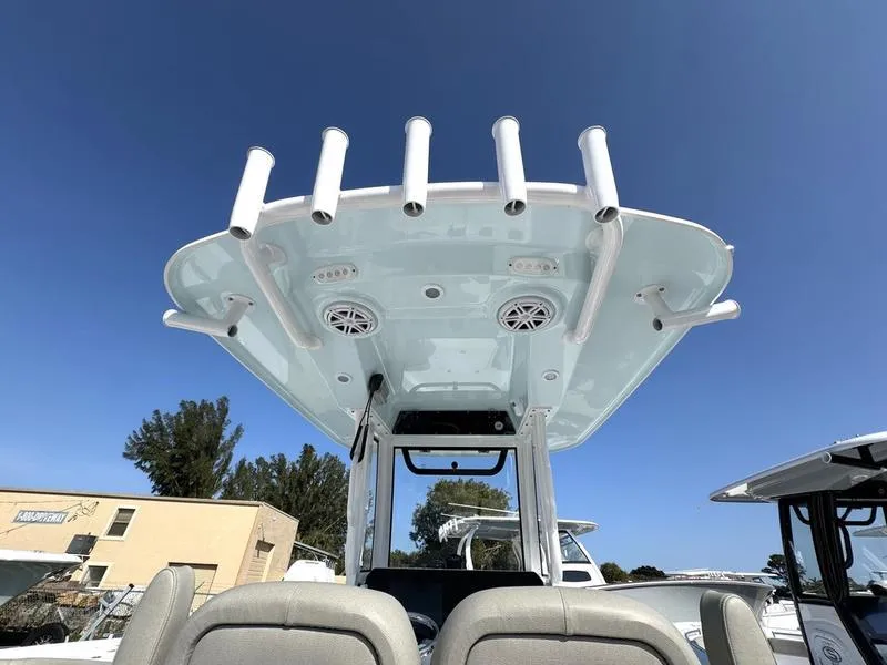 Slide: The Image of 2025 Sportsman Masters 227 boat with rod holders and speakers under a clear blue sky. - 25