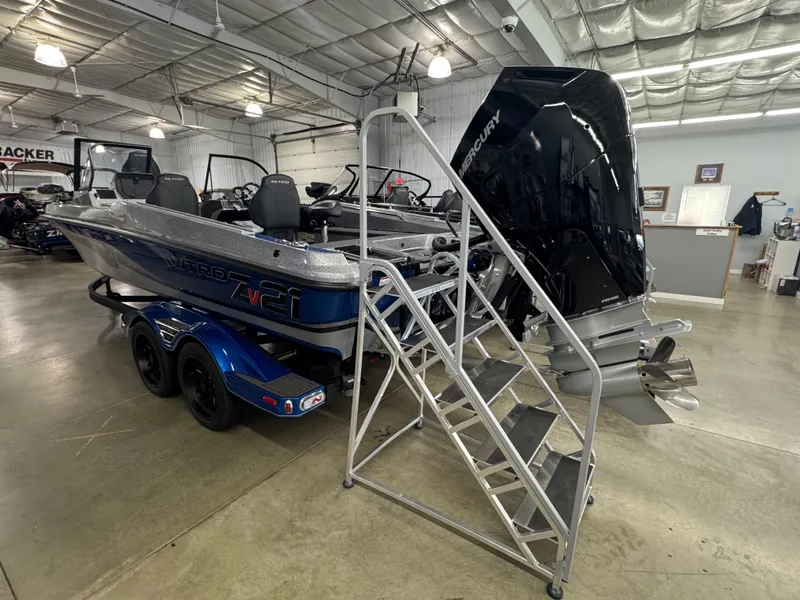 Slide: The Image of 2025 Nitro ZV21 boat in showroom with Mercury outboard motor and metal access stairs. - 2