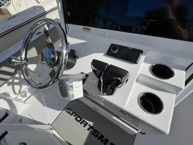 Slide: The Image of 2025 Sportsman Heritage 261 boat dashboard with steering wheel, controls, and cup holders. - 19