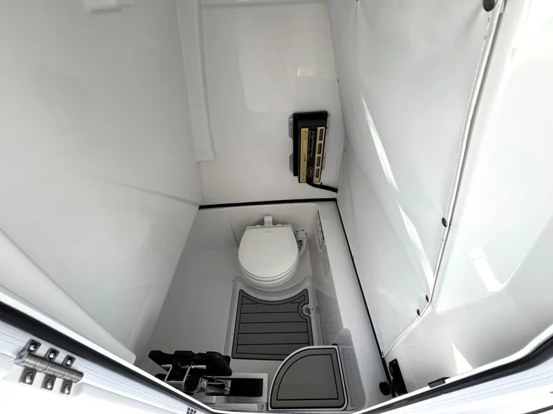 Slide: The Image of 2025 Sportsman Heritage 261 boat interior with compact marine toilet and storage. - 23