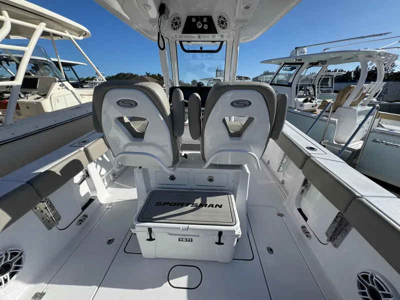 Slide: The Image of 2025 Sportsman Heritage 261 boat interior with seating and storage, docked under clear blue sky. - 28