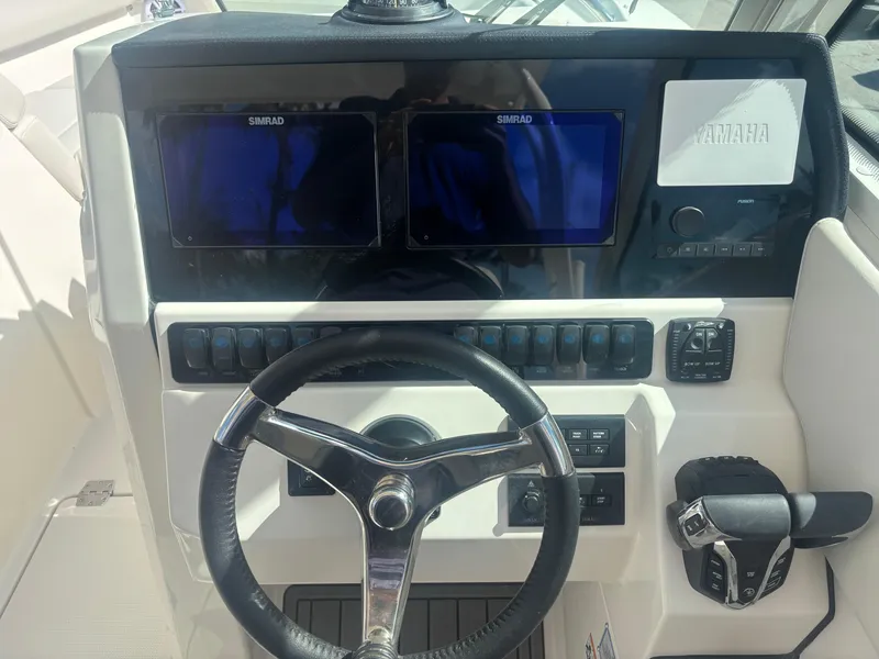 Slide: The Image of 2025 Sailfish 276 DC boat dashboard with steering wheel and dual Simrad displays. - 15