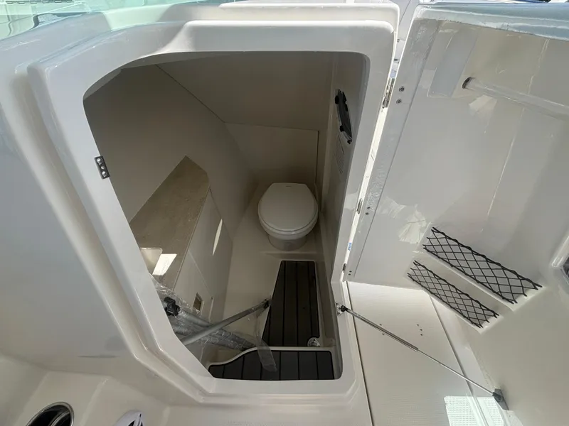 Slide: The Image of 2025 Sailfish 276 DC boat interior bathroom with toilet and storage space. - 19