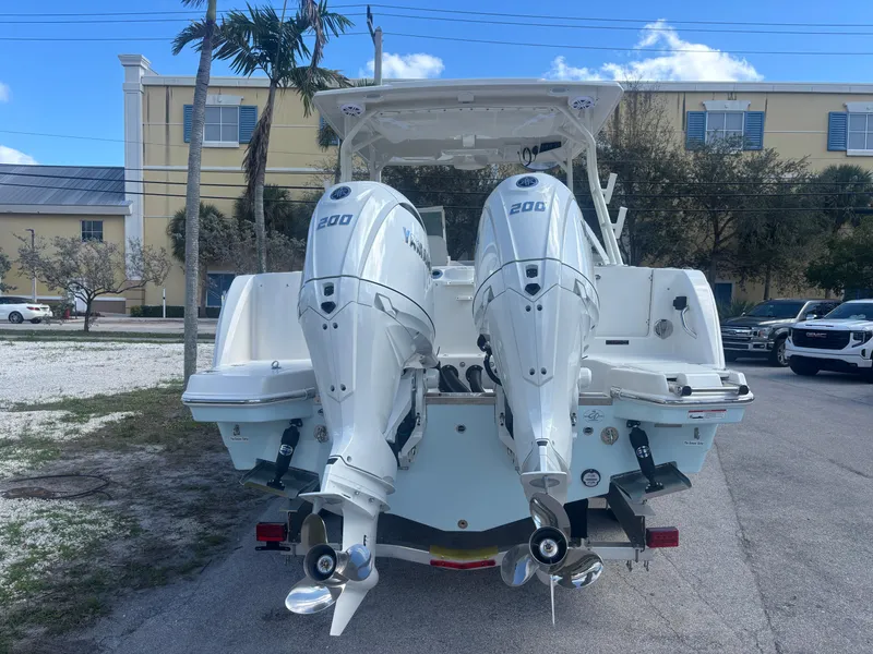Slide: The Image of 2025 Sailfish 276 DC boat with dual 200 horsepower engines, parked outdoors. - 2