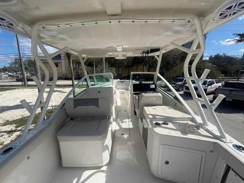 Slide: The Image of 2025 Sailfish 276 DC boat interior with seating and console, parked outdoors. - 22