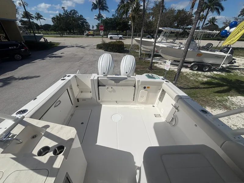 Slide: The Image of 2025 Sailfish 276 DC boat interior with seating and storage, parked outdoors. - 23