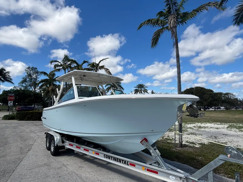Slide: The Image of 2025 Sailfish 276 DC boat on trailer under blue sky with palm trees. - 6
