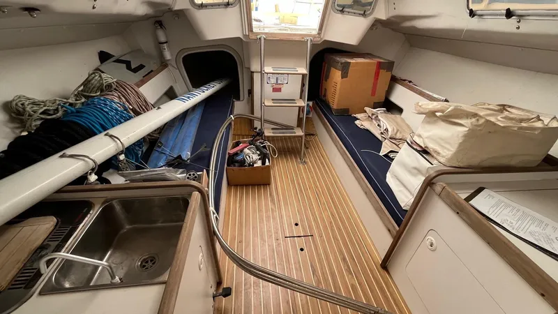 Slide: The Image of Interior of a 2000 J Boats J/105 sailboat with wooden flooring and storage items. - 13
