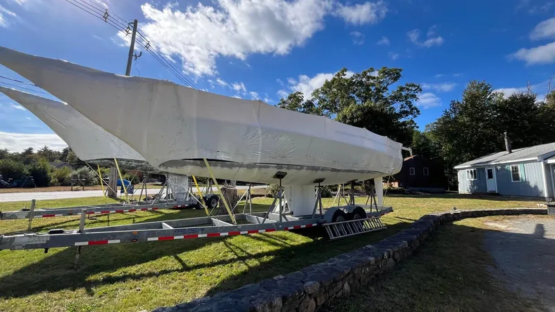 Slide: The Image of Covered 2000 J Boats J/105 sailboat on trailer, parked outdoors under blue sky. - 3