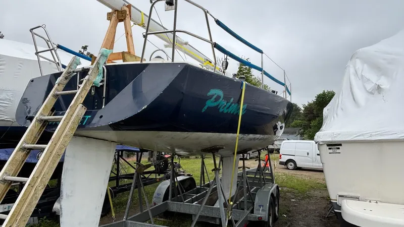 Slide: The Image of 2000 J Boats J/105 sailboat on trailer, parked outdoors under cloudy sky. - 30