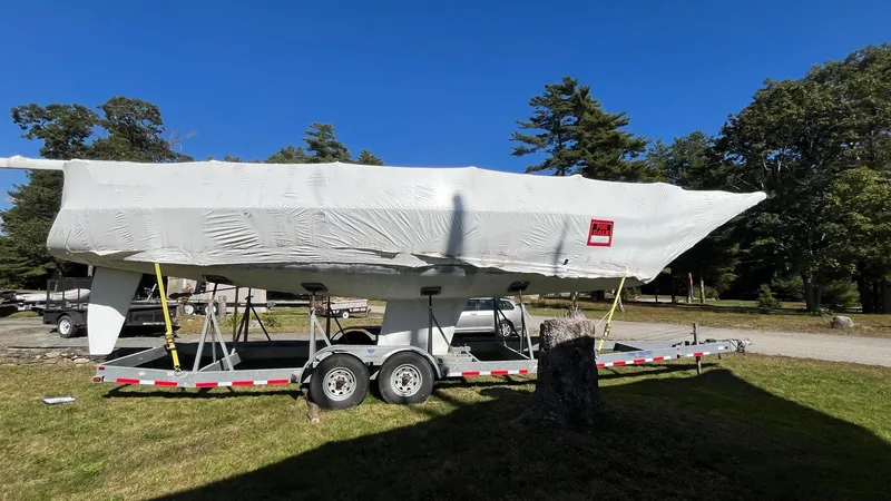 Slide: The Image of Covered 2000 J Boats J/105 sailboat on trailer, parked outdoors under clear blue sky. - 4