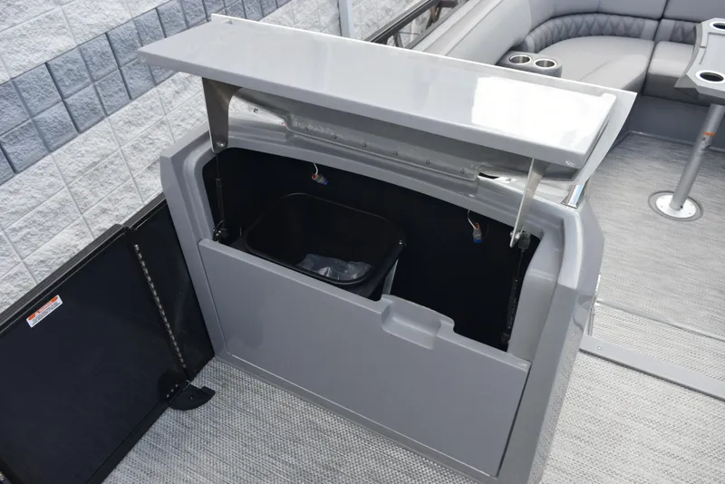 Slide: The Image of 2023 Bennington 25 RTFB boat storage compartment with open lid and trash bin. - 12