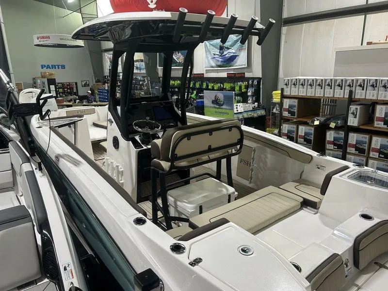 Slide: The Image of 2025 Yamaha Boats 255 FSH Sport H interior in showroom, featuring seating and control console. - 3