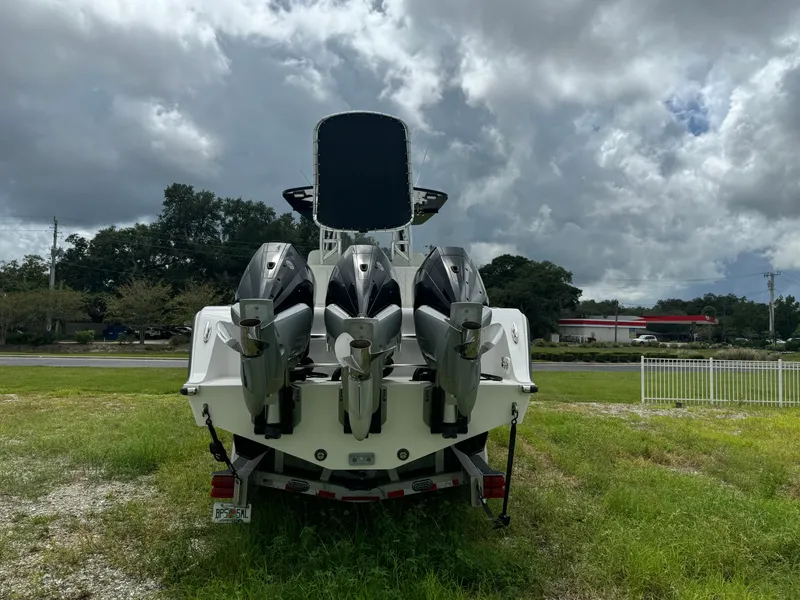 Slide: The Image of 2023 Front Runner 36 Center Console boat with triple outboard engines, parked on grass. - 4