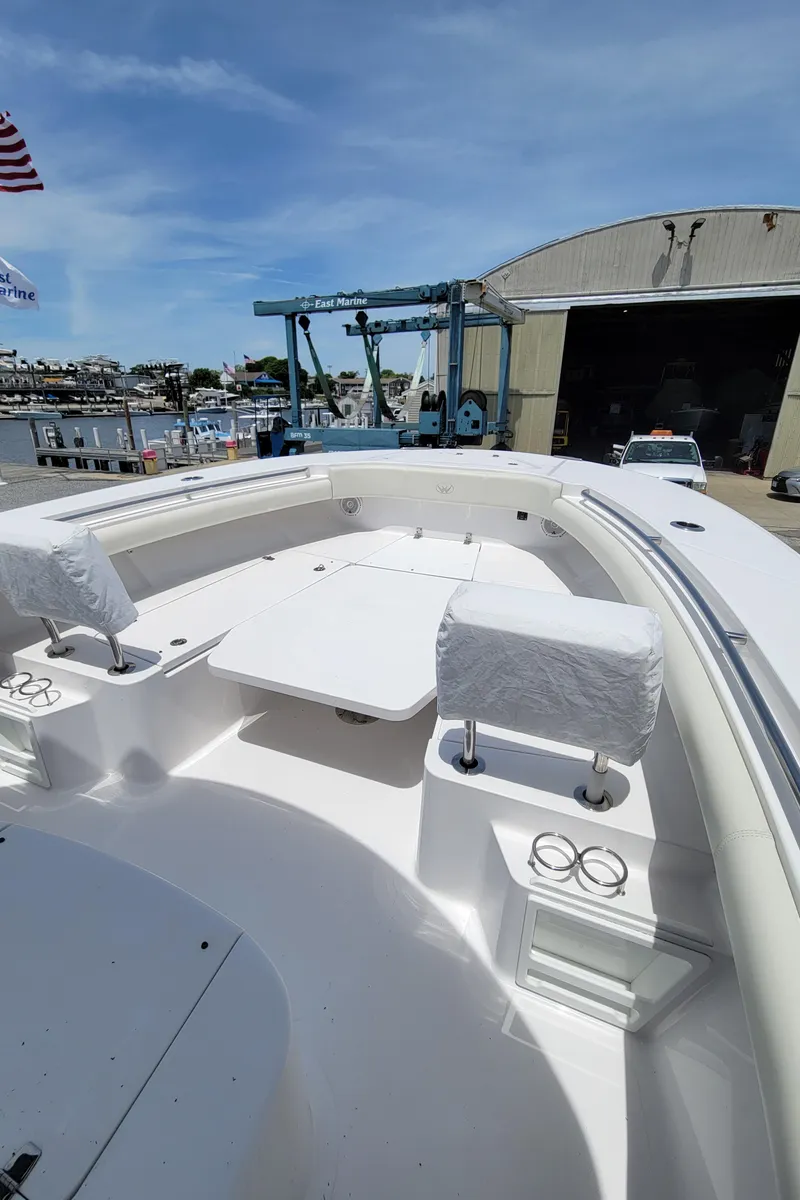 Slide: The Image of 2020 Southport 33 FE boat with spacious seating and table, docked near a marina. - 17