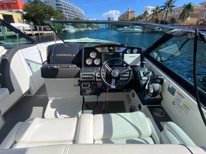 Slide: The Image of 2016 Formula 350 Crossover Bowrider cockpit with modern controls, docked by a scenic waterfront. - 21