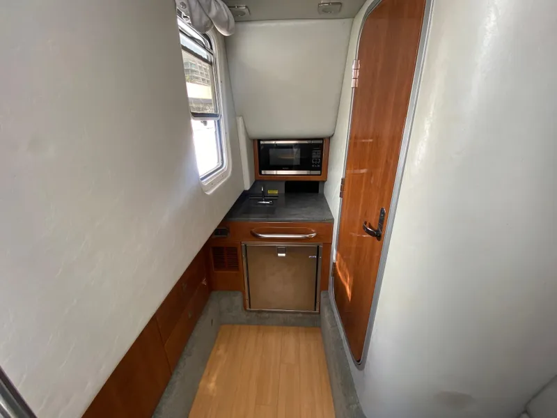 Slide: The Image of 2016 Formula 350 Crossover Bowrider interior with kitchenette, featuring microwave and compact fridge. - 25