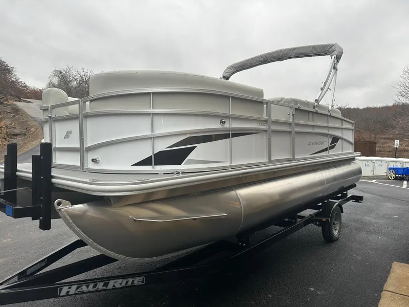 Slide: The Image of 2024 Starcraft LX 20 CB pontoon boat on trailer, parked outdoors. - 4