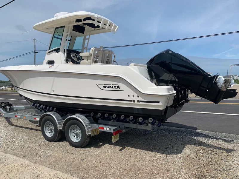 Slide: The Image of 2021 Boston Whaler 250 Outrage boat on trailer, parked outdoors. - 2
