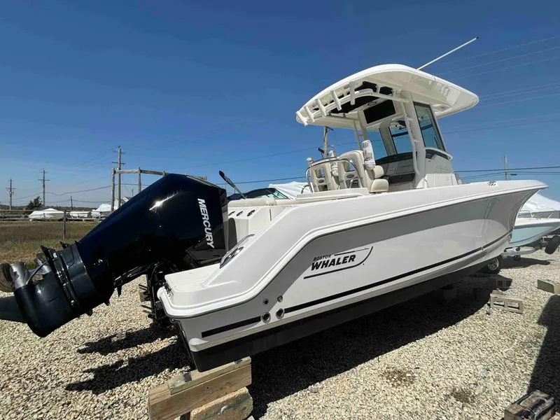 Slide: The Image of 2021 Boston Whaler 250 Outrage boat with Mercury engine, displayed outdoors on gravel. - 6