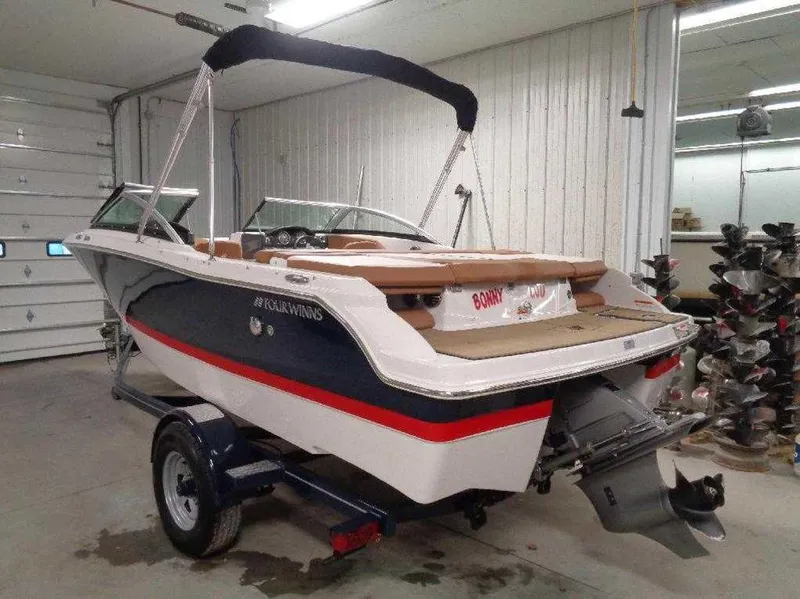 Slide: The Image of 2017 Four Winns Horizon 190 boat in a garage, featuring a sleek design and trailer. - 3
