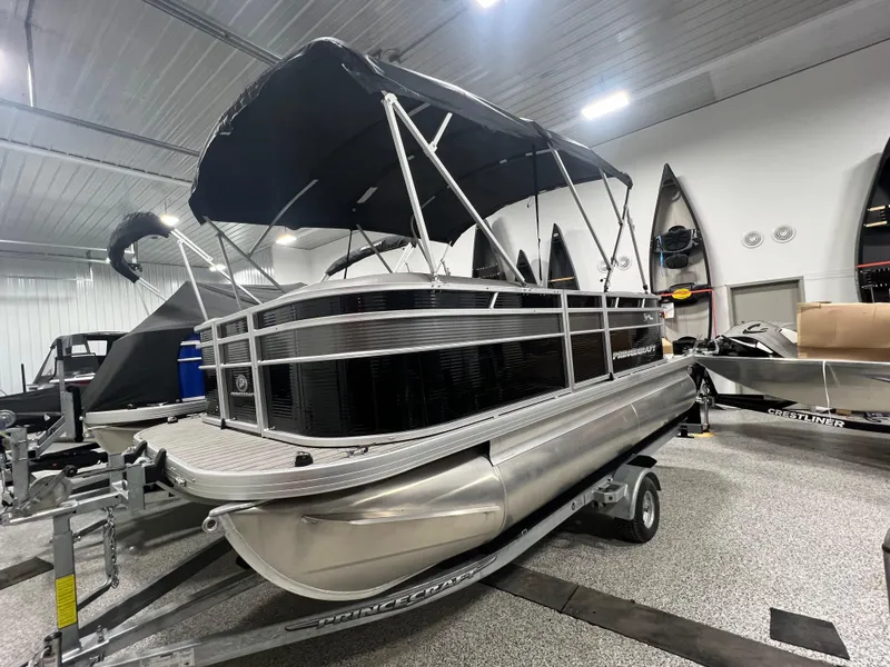 Slide: The Image of 2023 Princecraft Brio Electric 170 pontoon boat in showroom, featuring sleek design and canopy. - 0