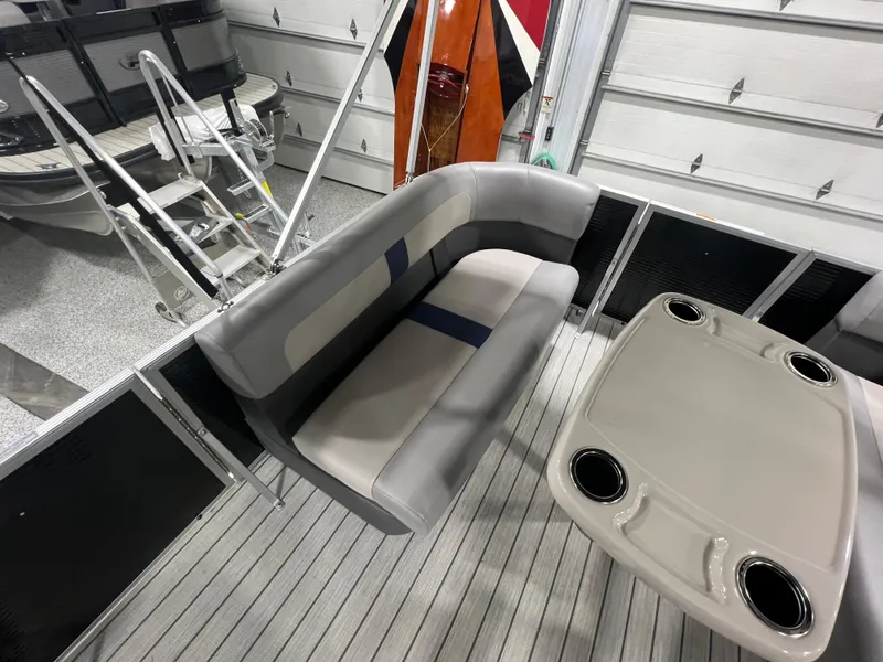 Slide: The Image of 2023 Princecraft Brio Electric 170 interior with gray seating and table in a garage setting. - 7