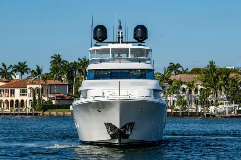 Slide: The Image of Luxury yacht Westport 112, 2002 model, cruising near waterfront homes and palm trees. - 2