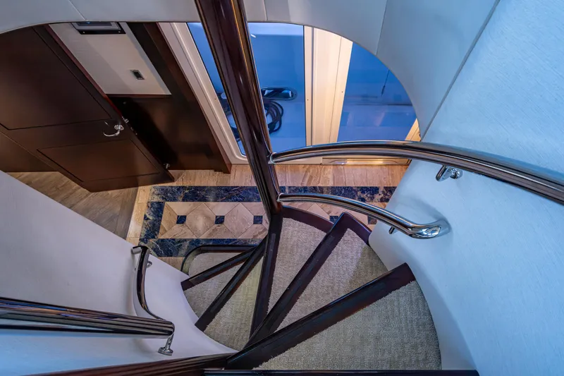 Slide: The Image of Spiral staircase inside 2002 Westport 112 yacht, featuring elegant wood and metal design. - 48